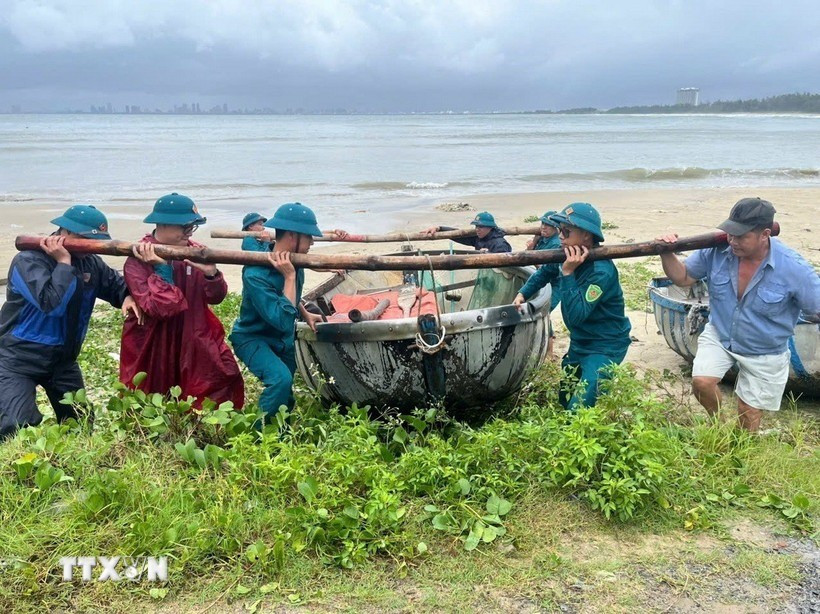 Lực lượng chức năng phường Hải Vân giúp ngư dân đưa thuyền thúng lên bờ tránh bão. (Ảnh: TTXVN phát) da-nang-bao-so-10.jpg