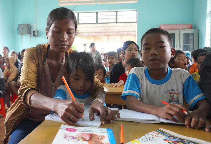 Ba mẹ con chị Kpuih Phơi cùng theo học lớp xóa mù chữ ở làng Khôi. Ảnh: Chu Hằng tinh-yeu-thuong.jpg