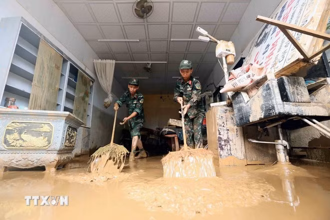 Lực lượng quân đội hỗ trợ người dân tổ 4, xã Sông Mã, Sơn La, thu gom bùn đất, cành cây, rác bị tràn về trong đợt lũ vừa qua. (Ảnh: Quang Quyết/TTXVN)