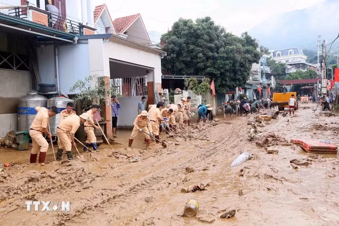 Lực lượng Cảnh sát giao thông tham gia thu gom bùn đất, cành cây, rác bị tràn về trong đợt lũ vừa qua tại xã Sông Mã, Sơn La. (Ảnh: Quang Quyết/TTXVN)