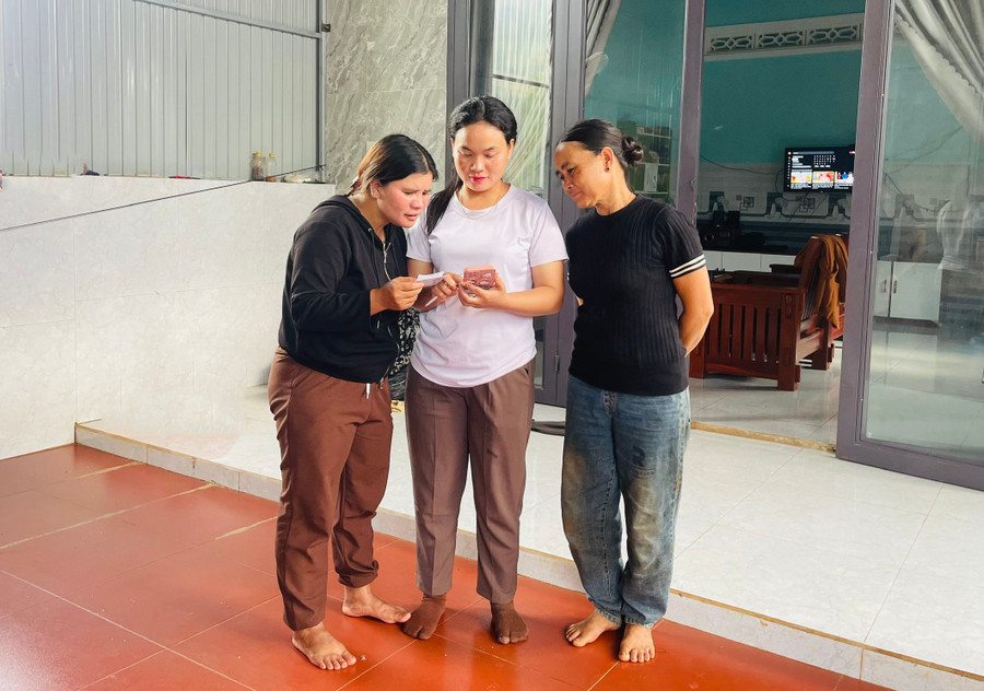 Chị H’Tinh (giữa) hướng dẫn người dân cài đặt định danh điện tử mức độ 2 tại nhà. Ảnh H.T 1-9006.jpg