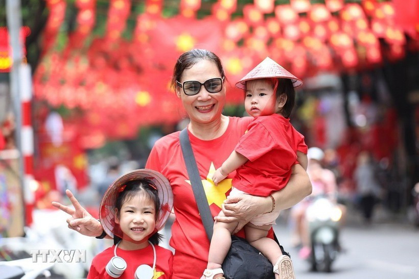 Nhiều người dân lưu lại khoảnh khắc với hình ảnh cờ Tổ quốc tại phố Hàng Mã, phường Hoàn Kiếm, Hà Nội. (Ảnh: Khánh Hòa/TTXVN) quoc-khanh.jpg