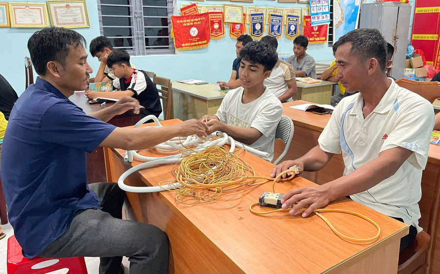 Pan Nay Tuy (pravá obálka) a studenti ve třídě se účastní procvičování zapojování elektrických vodičů. Foto: Vu Chi nong-dan.jpg