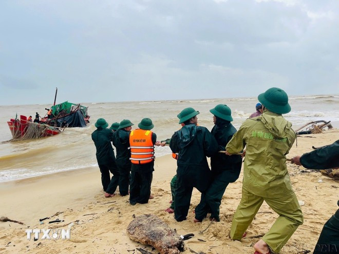 Chiến sỹ Đồn Biên phòng Nhật Lệ, tỉnh Quảng Trị giúp ngư dân kéo tàu cá bị chìm về bờ (11/2025). Nguồn: TTXVN