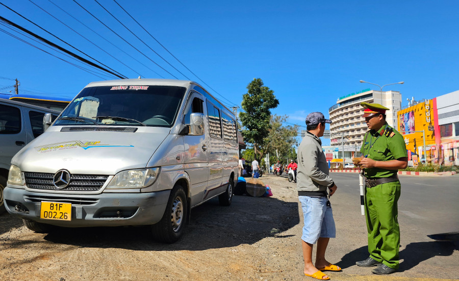 Lực lượng chức năng lập biên bản vi phạm đối với tài xế xe khách vi phạm đón trả khách không đúng nơi quy định. Ảnh: Bá Bính