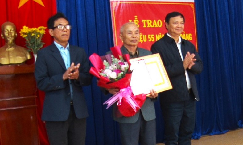 Bí thư Huyện ủy Nguyễn Huy Châu trao Huy hiệu 55 năm tuổi Đảng và tặng hoa chúc mừng đảng viên Nguyễn Văn Tìu. Ảnh: Minh Hải