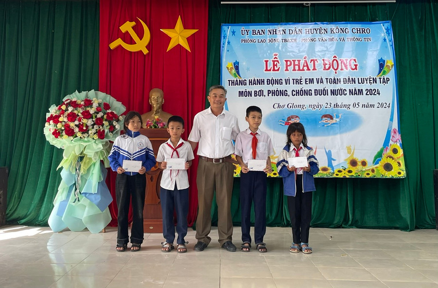Trưởng Phòng Lao động-Thương binh và Xã hội huyện tặng học bổng của Quỹ Bảo trợ trẻ em tỉnh cho các em học sinh. Ảnh: Phương Liên