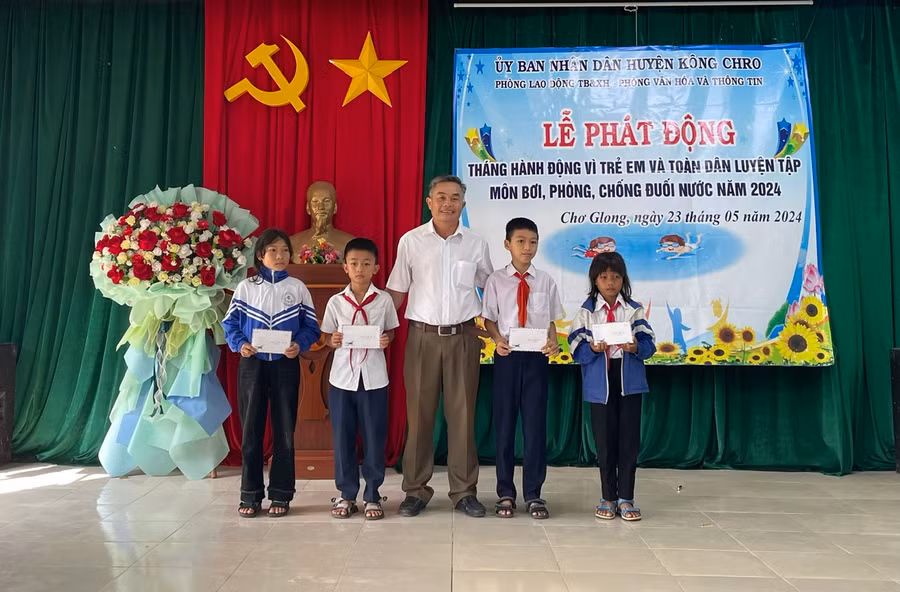 Trưởng Phòng Lao động-Thương binh và Xã hội huyện tặng học bổng của Quỹ Bảo trợ trẻ em tỉnh cho các em học sinh. Ảnh: Phương Liên