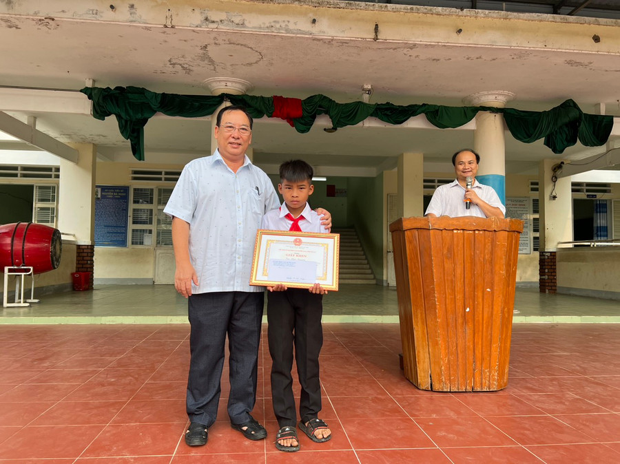 Phó Chủ tịch UBND huyện Ia Pa Trần Quốc Tuấn trao giấy khen và tiền thưởng cho em Kpă Nguyên. Ảnh: Như Loan Phó Chủ tịch UBND huyện Ia Pa Trần Quốc Tuấn trao giấy khen và tiền thưởng cho em Kpă Nguyên. Ảnh: Như Loan
