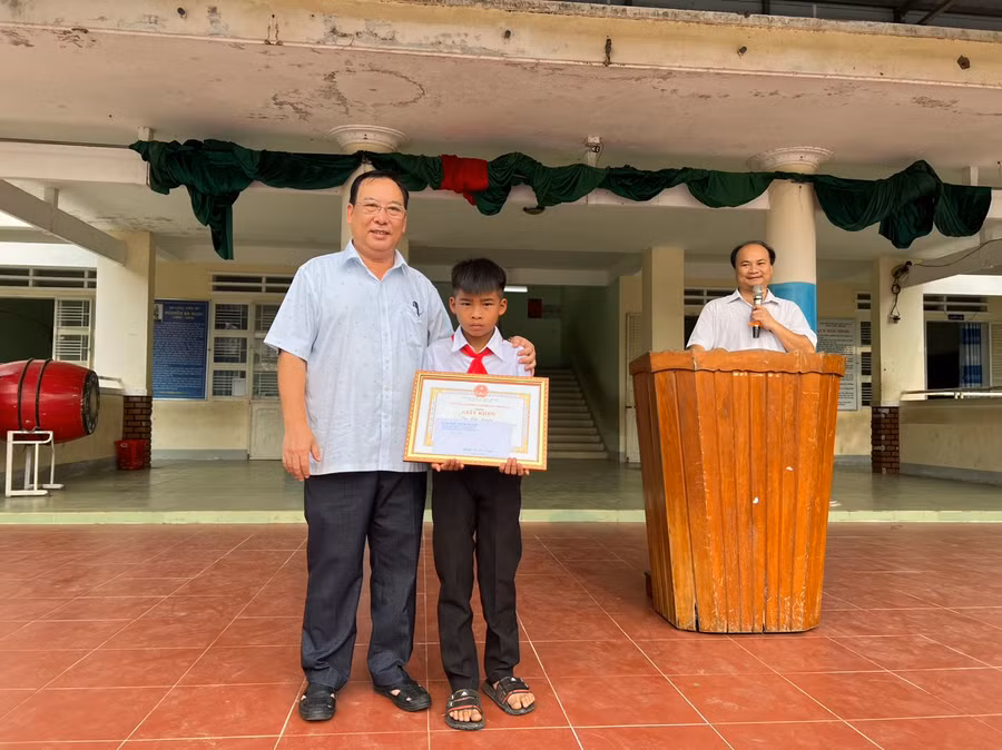 Phó Chủ tịch UBND huyện Ia Pa Trần Quốc Tuấn trao giấy khen và tiền thưởng cho em Kpă Nguyên. Ảnh: Như Loan