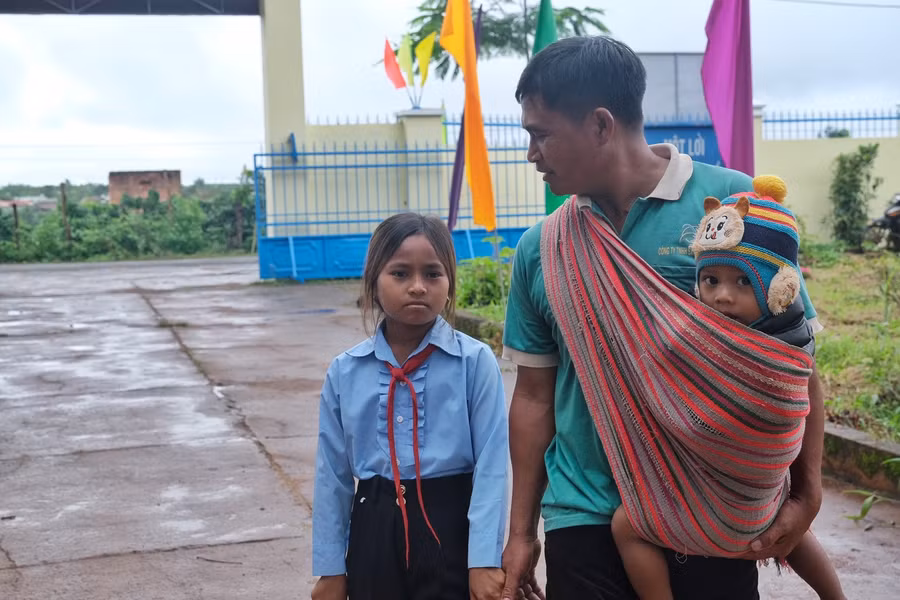 Anh Đinh Brơt (làng Thoong, xã Ia Tiêm) dắt tay con gái đến dự lễ khai giảng của Trường THCS và THPT Nguyễn Văn Cừ (huyện Chư Sê). Ảnh: Hoàng Ngọc