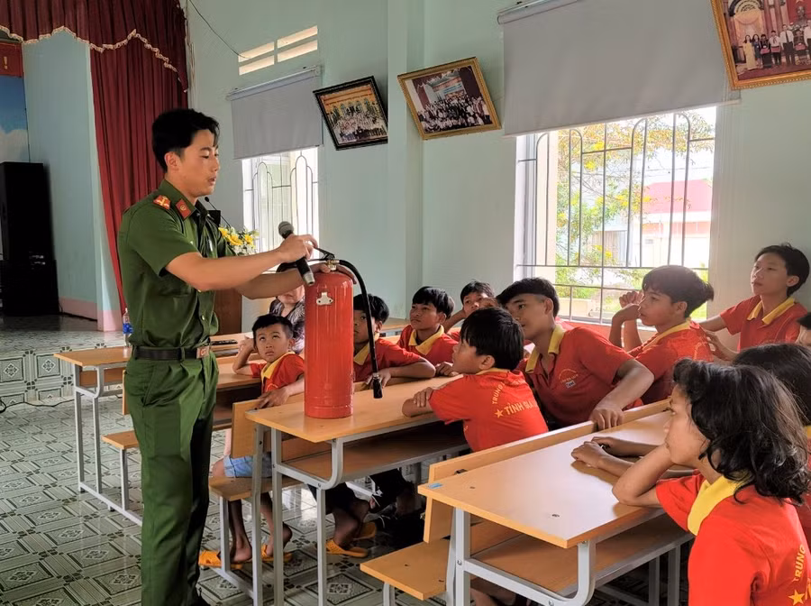 Cán bộ Công an hướng dẫn cho các em cách sử dụng bình chữa cháy khi có cháy nổ xảy ra. Ảnh: Hà Đức Thành