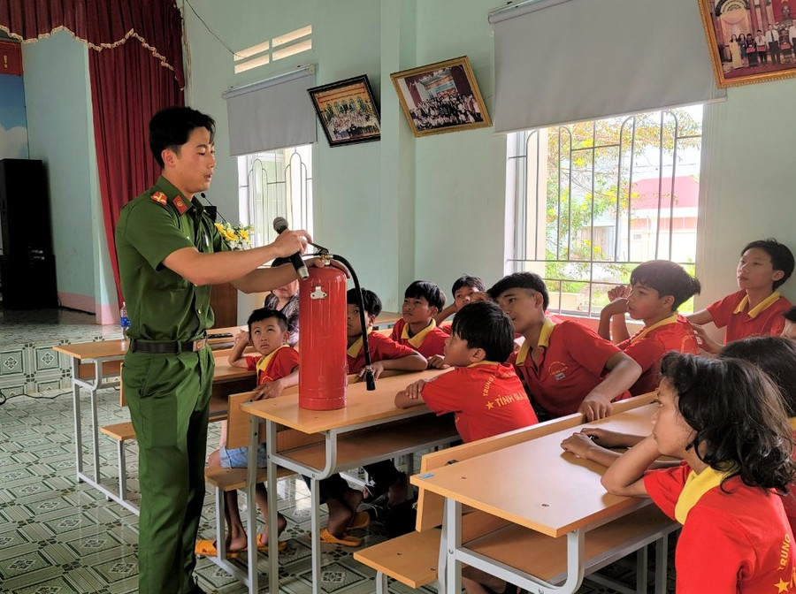 Cán bộ Công an hướng dẫn cho các em cách sử dụng bình chữa cháy khi có cháy nổ xảy ra. Ảnh: Hà Đức Thành