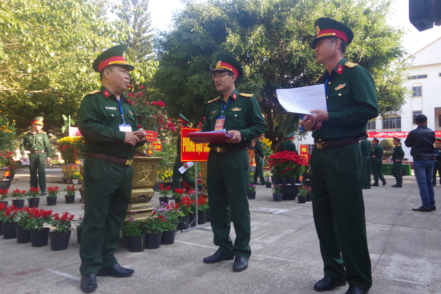 Đại tá Lê Tuấn Hiền-Chính ủy Bộ CHQS tỉnh (bìa trái) trao đổi kinh nghiệm trồng và chăm sóc hoa cho các đơn vị. Ảnh: Huy Bắc