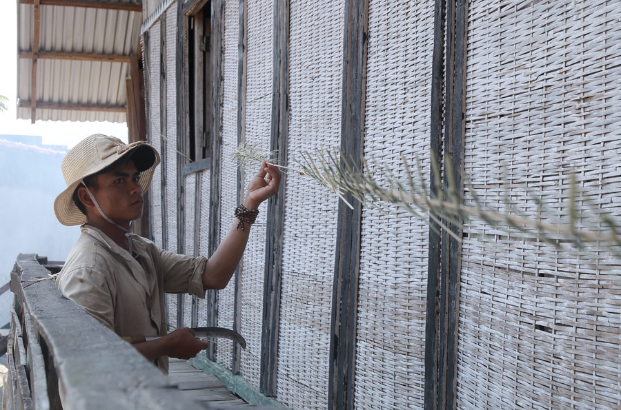 Anh Henh khéo léo đan bện dây cúng để trang trí cây nêu. Ảnh: Phương Linh