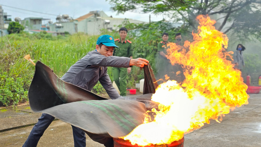 Học viên tham gia thực hành sử dụng chăn chiên để dập tắt đám cháy trong phi xăng. Ảnh: Bá Bính