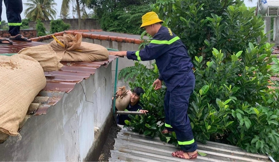Lực lượng Cảnh sát PCCC và CNCH tiến hành gia cố mái nhà cho người dân. Ảnh: Minh Thành