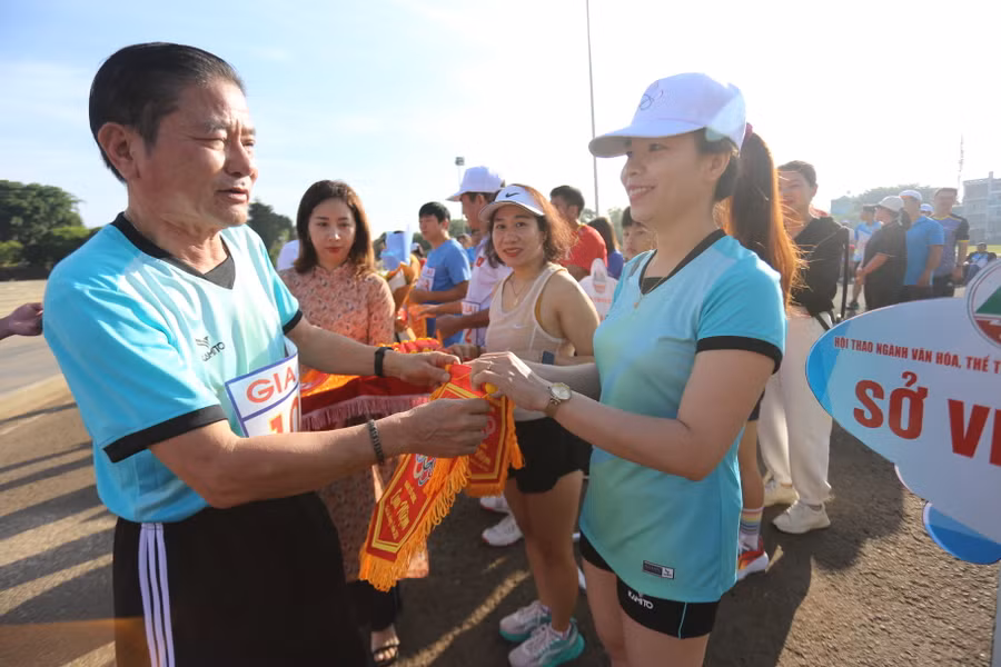 Ban tổ chức trao cờ lưu niệm cho các đoàn tham gia hưởng ứng Ngày chạy Olympic. Ảnh: Văn Ngọc