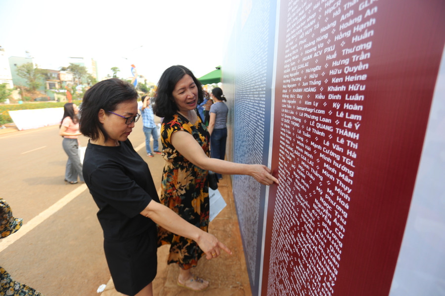 Các VĐV tìm tên của mình và người thân ở bảng ghi danh của giải. Ảnh: Văn Ngọc