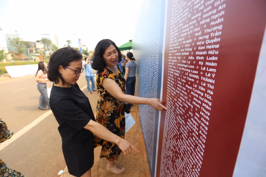 Các VĐV tìm tên của mình và người thân ở bảng ghi danh của giải. Ảnh: Văn Ngọc