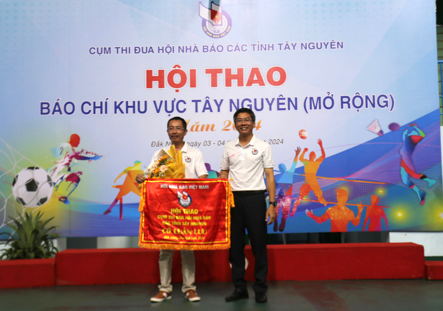 Đại diện lãnh đạo Hội Nhà báo tỉnh Gia Lai (trái) nhận cờ đăng cai Hội thao năm 2025 của Ban tổ chức. Ảnh: Văn Ngọc