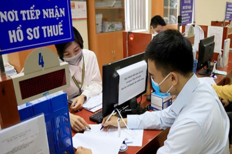 Công chức hướng dẫn người dân kê khai thủ tục nộp thuế. Ảnh: T.L 5-8036.jpg