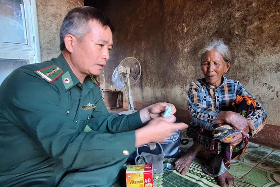 Trung tá Lâm Mạnh Tuyển-Nhân viên Quân y Đồn Biên phòng Ia Chía hướng dẫn bà Puih Yơng (làng Beng, xã Ia Chía) sử dụng thuốc nhỏ mắt. Ảnh: H.S