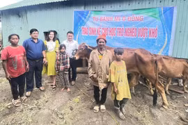 Thầy Vũ Văn Tùng (thứ 5 từ trái sang) phối hợp với Ban Giám hiệu Trường Tiểu học và THCS Lê Văn Tám trao sinh kế cho 2 học sinh nghèo vượt khó của trường. Ảnh: NVCC