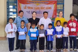 Thầy Vũ Văn Tùng (hàng sau, thứ 3 từ trái sang, người phụ trách "Tủ bánh mì 0 đồng") phối hợp với Ban Giám hiệu Trường Tiểu học và THCS Lê Văn Tám trao học bổng cho học sinh vượt khó học giỏi của trường. Ảnh: Văn Tùng