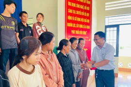 Bí thư Đảng ủy xã Phạm Văn Phương trao tặng thẻ bảo hiểm y tế cho các công dân bị ngộ độc thực phẩm. Ảnh: Vũ Chi