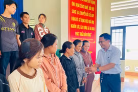 Bí thư Đảng ủy xã Phạm Văn Phương trao tặng thẻ bảo hiểm y tế cho các công dân bị ngộ độc thực phẩm. Ảnh: Vũ Chi