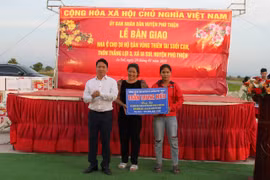 Bí thư Huyện ủy Trần Trung Hiếu trao bảng tượng trưng kinh phí 120 triệu đồng hỗ trợ các hộ dân Suối Cạn xây dựng nhà ở tại khu tái định cư mới. Ảnh: Vũ Chi