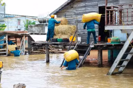 Lực lượng dân quân xã Ia Hiao hỗ trợ người dân vùng ngập lụt di dời lương thực lên trên nhà sàn. Ảnh: ĐVCC