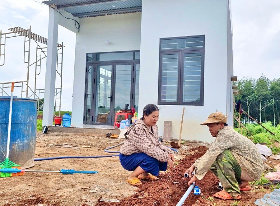Bà Nguyễn Thị Mỹ Trang lắp đặt hệ thống dẫn nước sạch vào ngôi nhà mới xây tại khu tái định cư làng Ar Trớ (xã Lơ Pang). Ảnh: Minh Phương gia-dinh-ba-trang.jpg