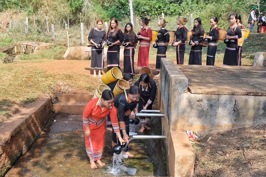 Phụ nữ trong làng thực hiện nghi thức lấy nước vào bầu khô với mong muốn nguồn nước luôn dồi dào, tuôn chảy. Ảnh: Hoàng Ngọc