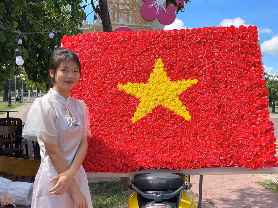 Bạn Dương Thị Kim Ngân (thôn Hải Yên, xã Chư A Thai, huyện Phú Thiện) vượt quãng đường hơn 10 km đến check in cùng lá cờ Tổ quốc được kết từ hoa tươi tại Quảng trường huyện. Ảnh: Vũ Chi