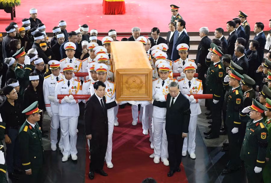 Tổng Bí thư Tô Lâm, Chủ tịch nước Lương Cường đặt tay lên linh cữu, đưa tiễn nguyên Chủ tịch nước Trần Đức Lương ra ngoài nhà tang lễ, phía sau là gia quyến và các đại biểu. ẢNH: GIA HÂN