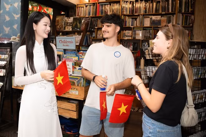 Du khách quốc tế được tặng cờ đỏ sao vàng khi du lịch Thành phố Hồ Chí Minh cuối tháng Tư vừa qua. (Ảnh: CTV/Vietnam+)