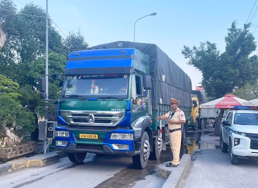 Cán bộ Trạm Cảnh sát giao thông Tuy Phước hướng dẫn tài xế điều khiển phương tiện vào cân tải trọng. Ảnh: K.A