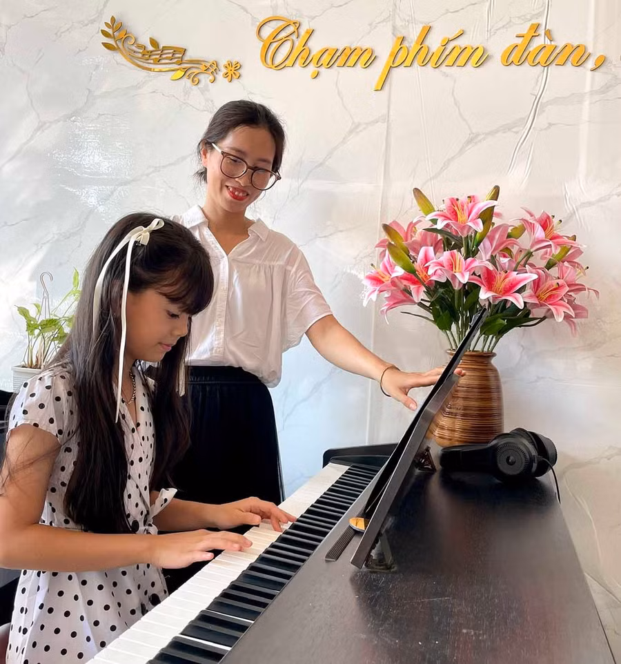 Cô giáo Trần Thị Thanh Thảo bên một học viên ở lớp dạy đàn tại nhà.