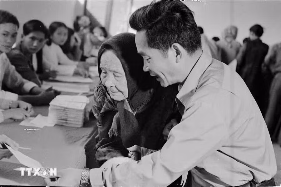Ngày 25/4/1976, trên 23 triệu cử tri của nước Việt Nam thống nhất đã nô nức đi bầu cử. Đây thực sự là ngày hội lớn của toàn dân Việt Nam. Trong ảnh: Cụ Lê Thị Dưỡng (86 tuổi, thành phố Huế), già yếu vẫn nhờ người cõng đến hòm phiếu tham gia bầu cử đại biểu Quốc hội thống nhất (25/4/1976). (Ảnh: Sỹ Thái/TTXVN)