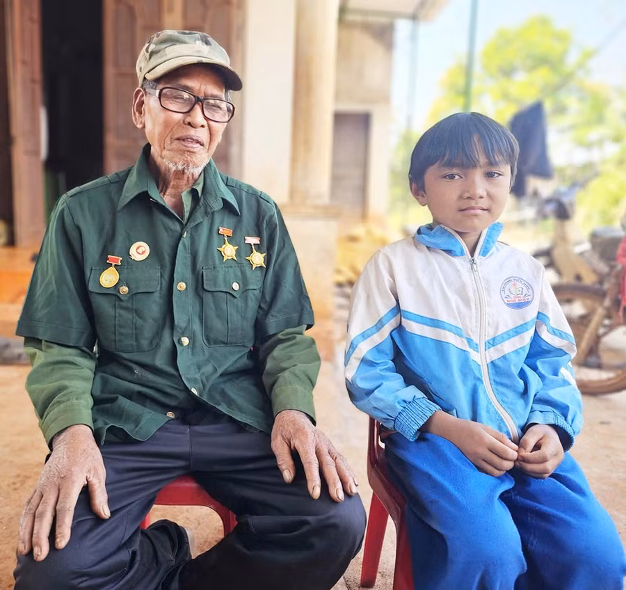 Ông Rơ Châm Hăng kể lại cho cháu trai của mình về những năm tháng chiến đấu. Ảnh: R’Ô HOK