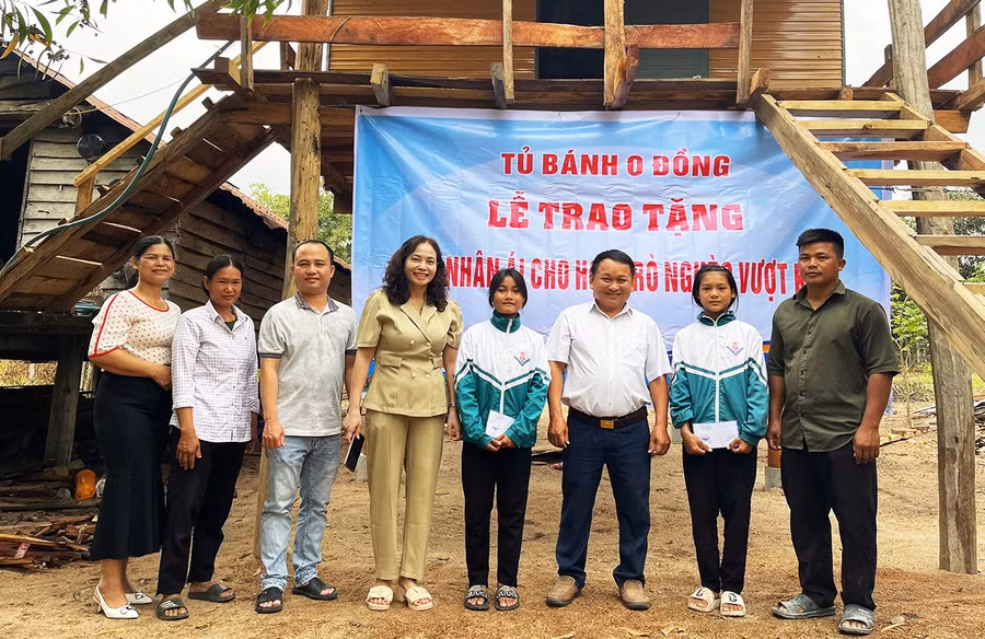 Thầy Vũ Văn Tùng (thứ 3 từ phải sang, người đại diện Tủ bánh mì 0 đồng) trao tặng nhà nhân ái, học bổng cho em Nay H’Ngan (thứ 2 từ phải sang) và Ksor H’Nhí (thứ 4 từ phải sang). Ảnh: Vũ Chi