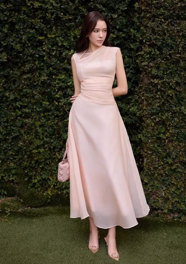 Đầm xòe tơ gân màu hồng pastel có điểm nhấn là chi tiết nhún vai cổ xéo, xếp nếp tôn eo thon giúp nàng thu hút trọn sự chú ý. Với thiết kế này, tính ứng dụng hoàn toàn do nàng quyết định - mặc đi làm, đi chơi hay đi tiệc đều phù hợp và sang xịn miễn bàn. ẢNH: MAYBI