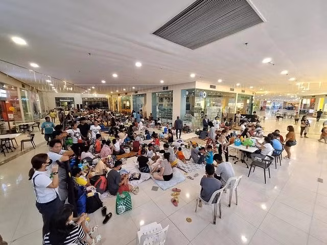 Người dân trú ẩn bên trong một trung tâm thương mại được dựng làm trung tâm sơ tán tạm thời tại thị trấn Polangui thuộc tỉnh Albay ngày 16.11 trước khi siêu bão Man-yi đổ bộ. Ảnh: AFP
