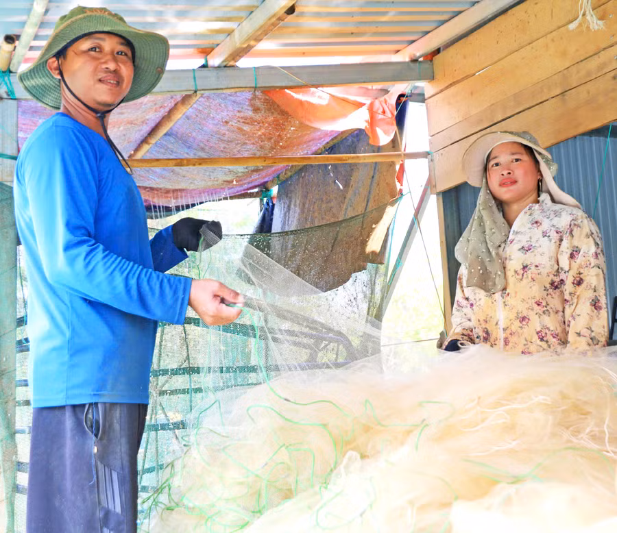 Vợ chồng anh Trần Văn Tuấn đang giũ lưới cá cơm sau khi đánh bắt. Ảnh: Đồng Lai