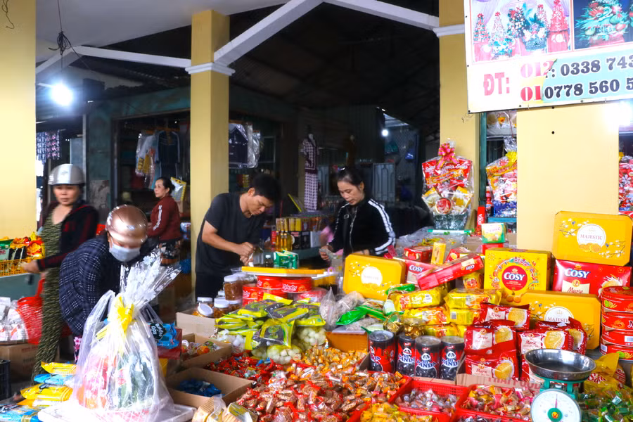 Chị Thân Thị Thu Thủy (bìa phải)-tiêu thương chợ Chí Công (thôn Hiệp An, xã Tân An, huyện Đak Pơ) tất bật tính tiền hàng cho khách. Ảnh: Ngọc Minh