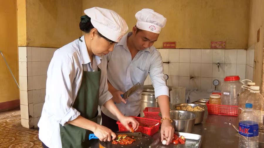 Chị Nga hướng dẫn nhân viên mới cách chế biến thức ăn. Ảnh: Vĩnh Hoàng