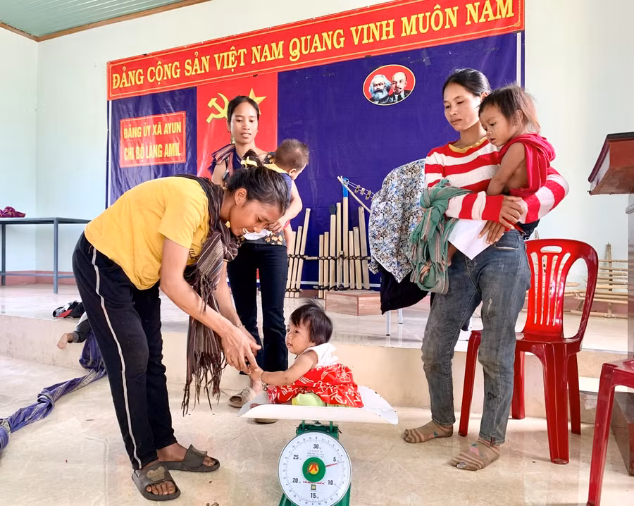 Nhân viên y tế kiểm tra cân nặng cho trẻ. Ảnh: Như Nguyện
