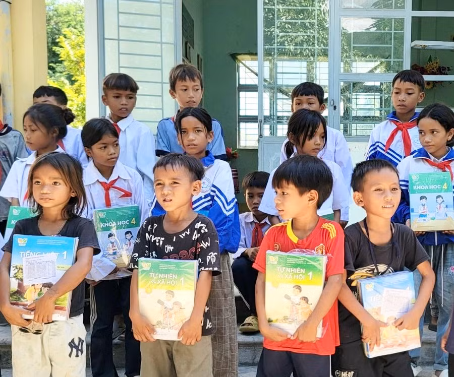 Các em học sinh phấn khởi nhận sách giáo khoa mới do chương trình trao tặng. Ảnh: Như Nguyện